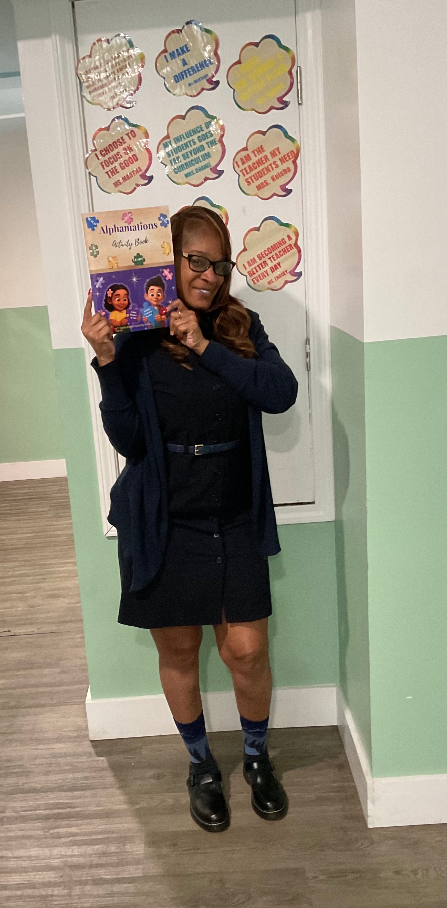 Teacher holding the Alphamations™ Faith-Filled Activity Book while introducing young learners to literacy, confidence, and Christian character development.